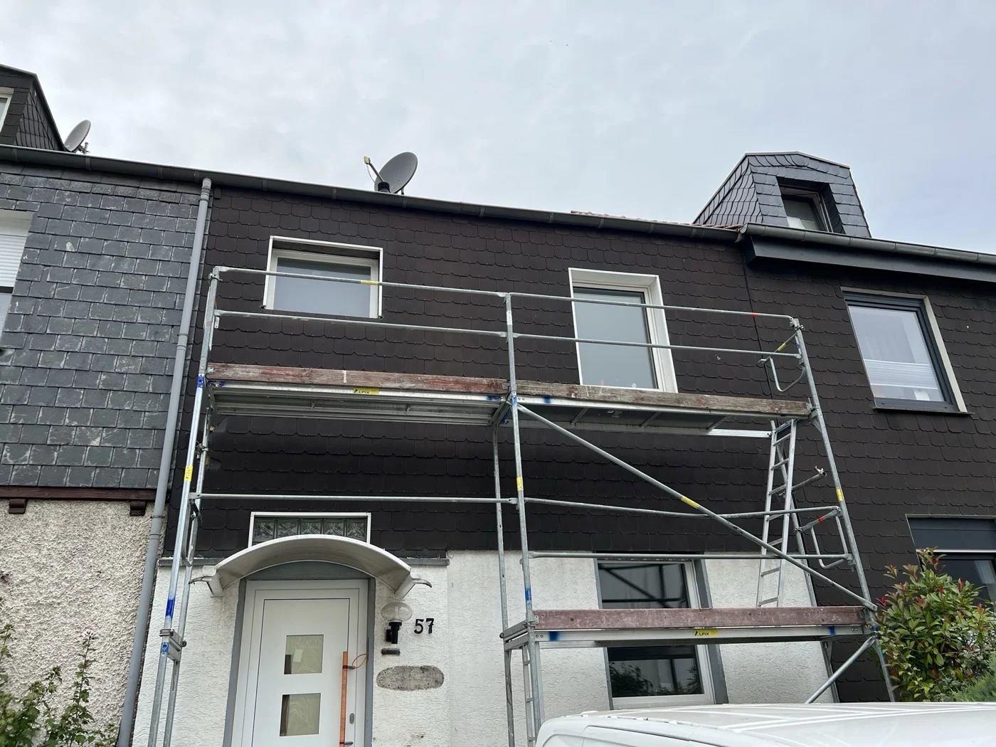 Fassadenrenovierung eines Mehrfamilienhauses mit dunkler Holzverkleidung und weißen Kunststofffenstern